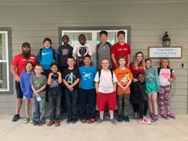 Group of children standing in front of the Craig Family Friendship House.